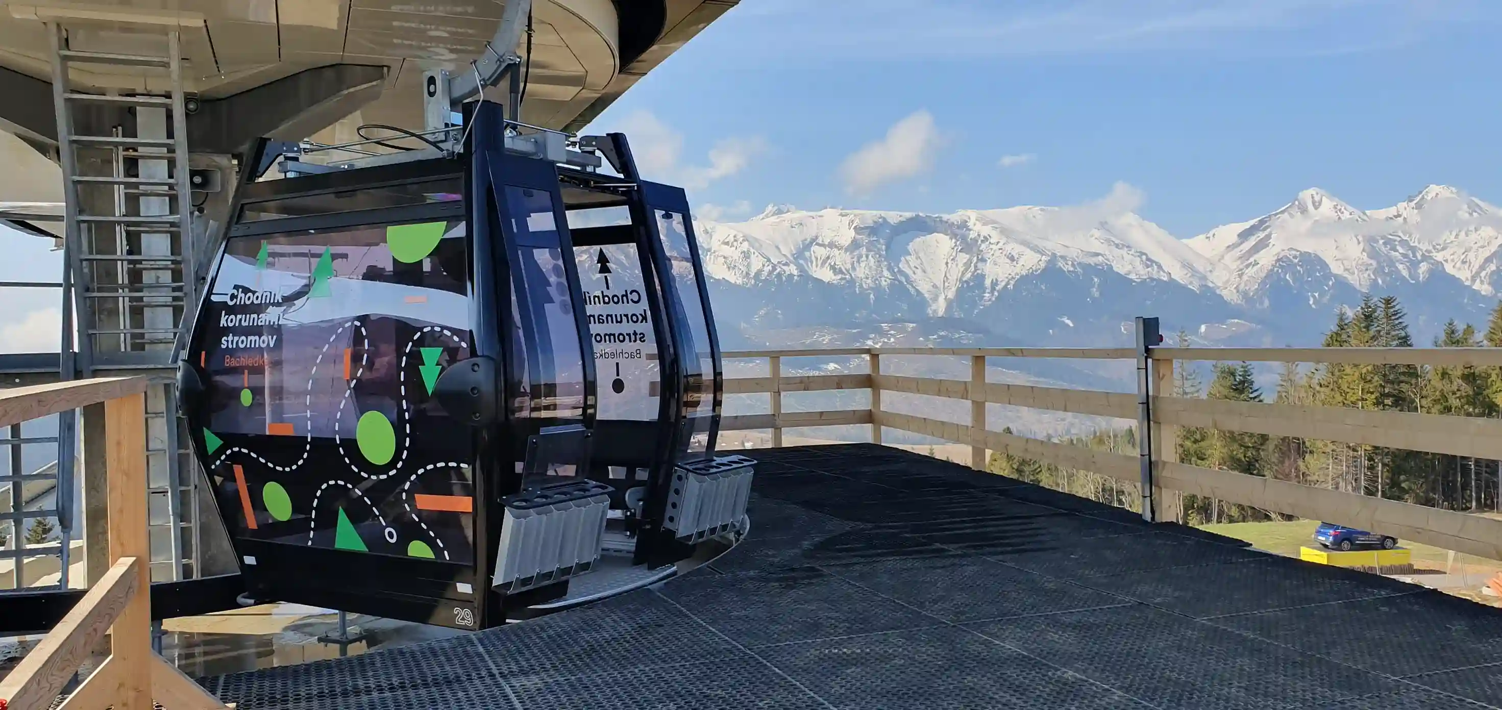 Kolejka linowa przemieszczająca się przez ośnieżony krajobraz z widokiem na góry pod czystym niebem.