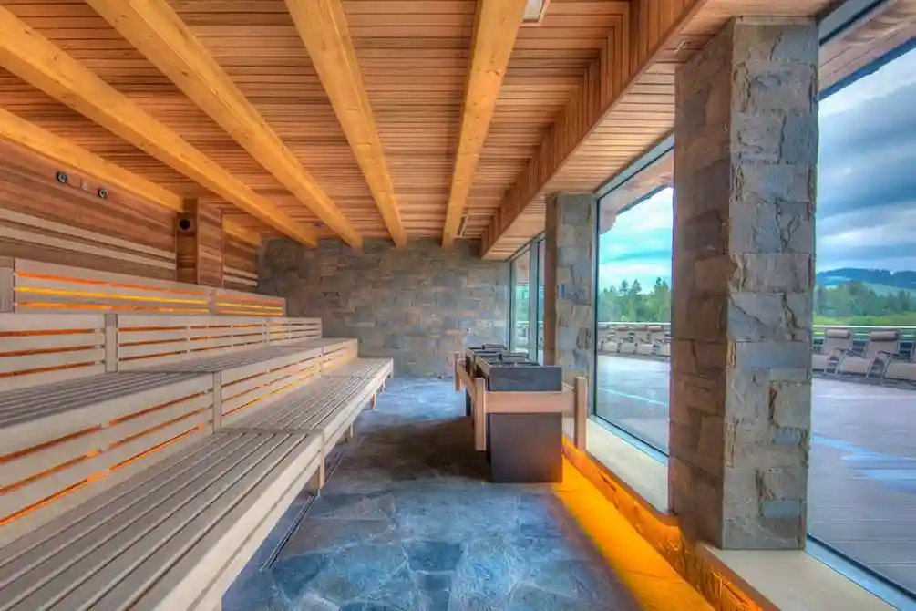 Drewniana ławka stoi w pomieszczeniu z sufitem i oknem, z elementami architektonicznymi na ścianach i podłodze.