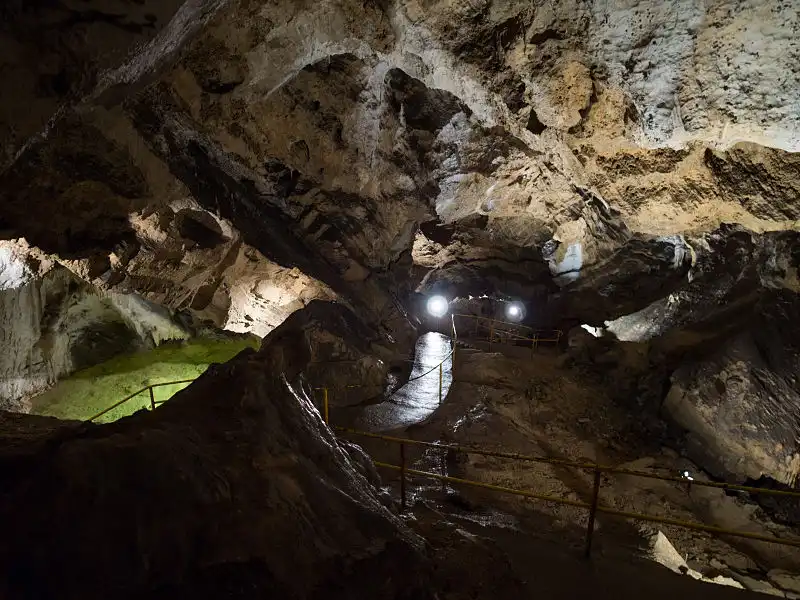 Wnętrze jaskini oświetlone światłem, prezentujące unikalne naturalne formacje w tubie lawowej.